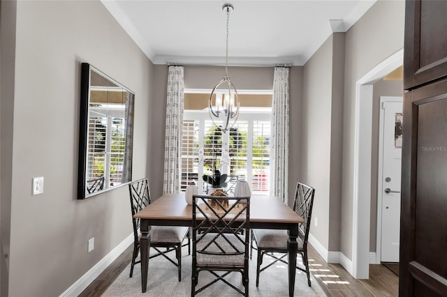 dining space with hardwood / wood-style flooring, ornamental molding, and an inviting chandelier