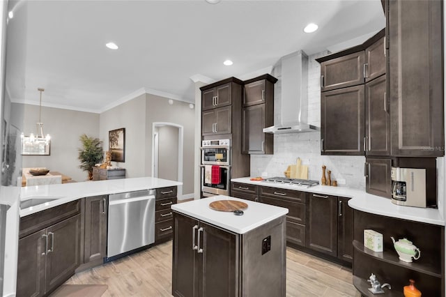 kitchen with stainless steel appliances, wall chimney range hood, light hardwood / wood-style flooring, backsplash, and crown molding