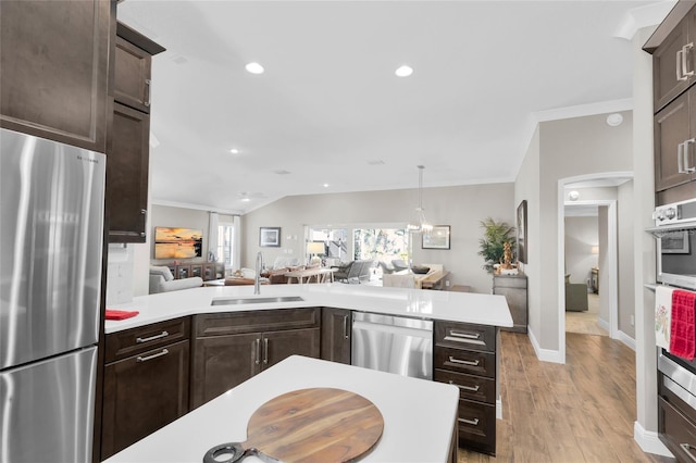 kitchen with kitchen peninsula, appliances with stainless steel finishes, dark brown cabinetry, sink, and light hardwood / wood-style floors