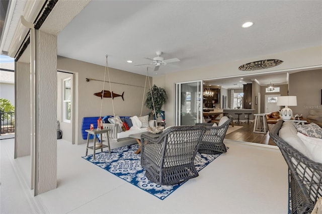 living room with ceiling fan with notable chandelier and a textured ceiling