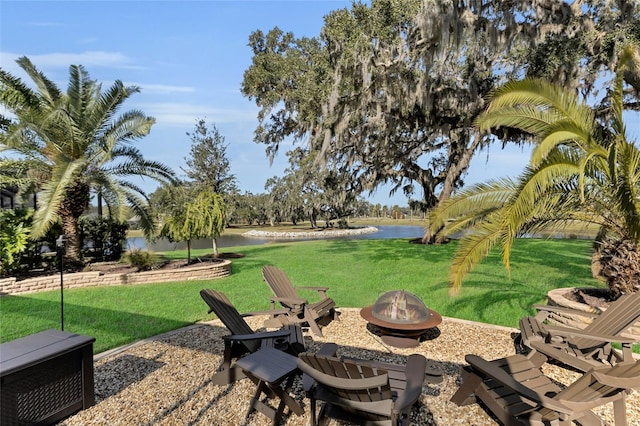 view of yard featuring a water view, a fire pit, and a patio area