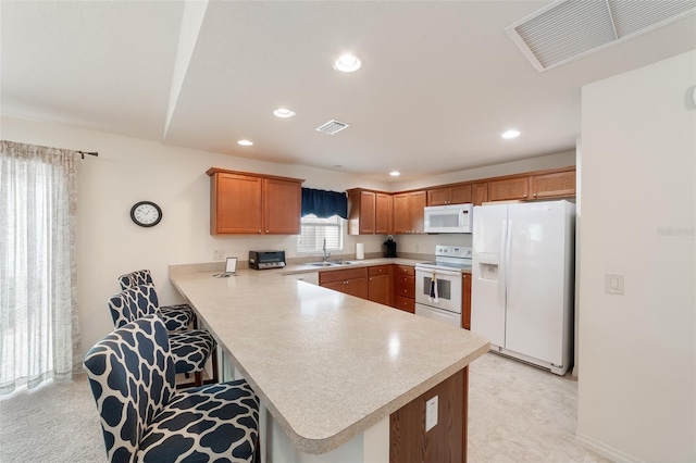 kitchen with a kitchen bar, kitchen peninsula, sink, and white appliances