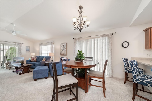 dining room with ceiling fan with notable chandelier, light colored carpet, and lofted ceiling