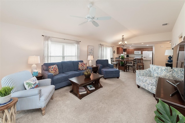 carpeted living room with ceiling fan with notable chandelier and lofted ceiling