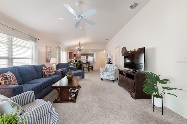 carpeted living room with ceiling fan with notable chandelier and lofted ceiling