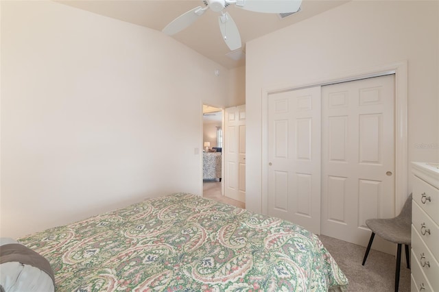 bedroom with ceiling fan, a closet, light colored carpet, and vaulted ceiling