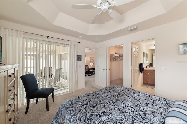 bedroom featuring access to outside, ceiling fan, a tray ceiling, light colored carpet, and a closet