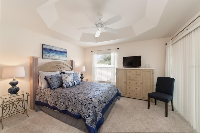 bedroom featuring a raised ceiling, ceiling fan, and light carpet