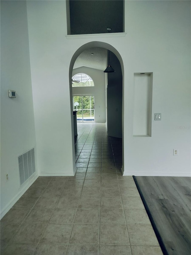 hall featuring light tile patterned floors and lofted ceiling