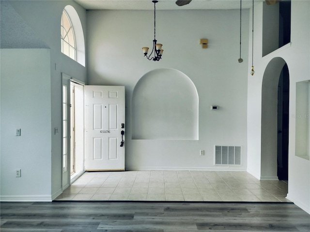 tiled foyer entrance featuring a towering ceiling and a notable chandelier