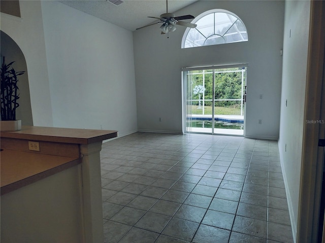 unfurnished living room featuring ceiling fan, light tile patterned floors, and high vaulted ceiling