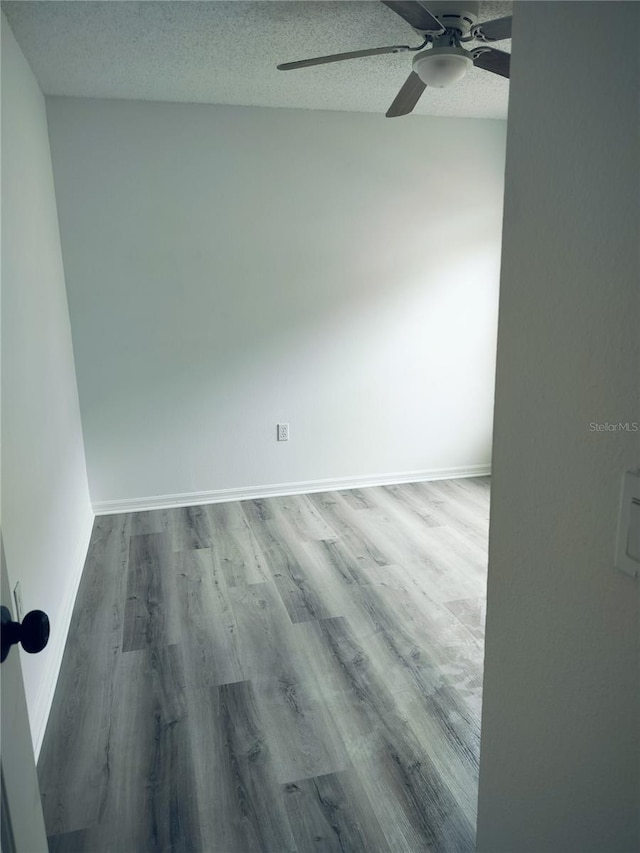 spare room featuring ceiling fan, wood-type flooring, and a textured ceiling