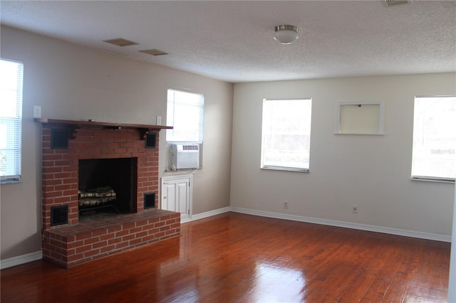 unfurnished living room with a fireplace, a textured ceiling, dark hardwood / wood-style floors, and cooling unit