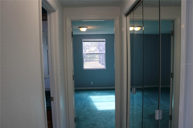 hall featuring carpet flooring and a textured ceiling