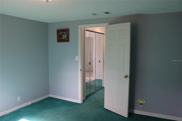 carpeted empty room featuring a textured ceiling