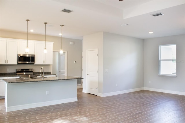 kitchen with a center island with sink, white cabinets, and appliances with stainless steel finishes