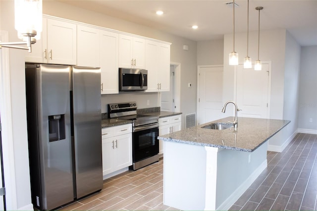 kitchen with appliances with stainless steel finishes, a center island with sink, white cabinetry, and sink