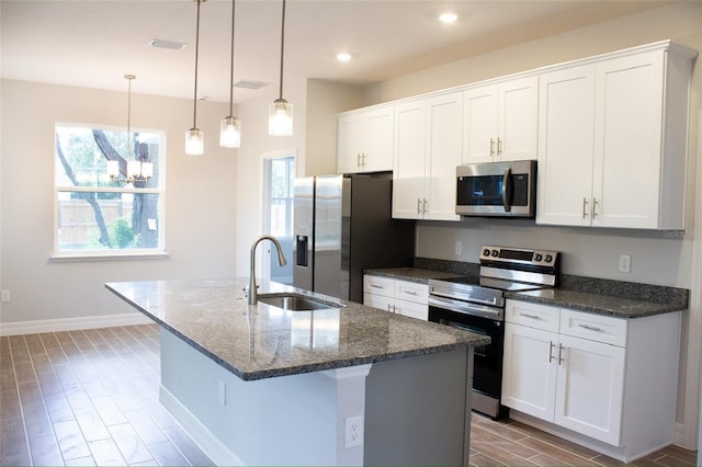 kitchen with a wealth of natural light, a center island with sink, and appliances with stainless steel finishes