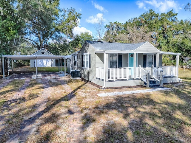 view of front of house featuring a carport, covered porch, central air condition unit, and a front yard