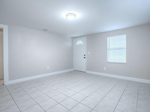 tiled empty room featuring a textured ceiling