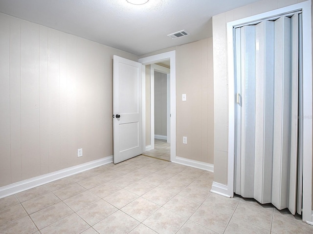 tiled empty room featuring a textured ceiling