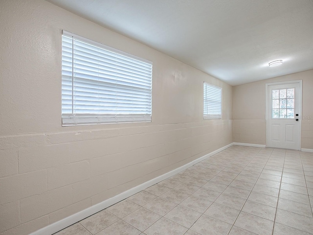 tiled spare room with vaulted ceiling