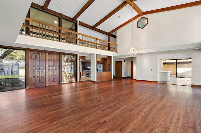 unfurnished living room featuring beamed ceiling, dark hardwood / wood-style floors, high vaulted ceiling, and a chandelier