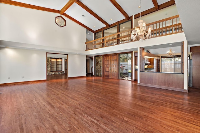 unfurnished living room featuring beam ceiling, dark hardwood / wood-style flooring, high vaulted ceiling, and a chandelier