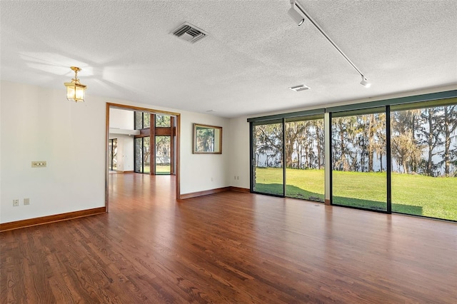 unfurnished room featuring plenty of natural light, dark hardwood / wood-style flooring, a textured ceiling, and track lighting