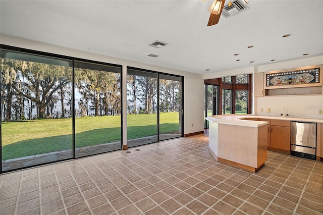 kitchen with ceiling fan, tile patterned flooring, a textured ceiling, and sink