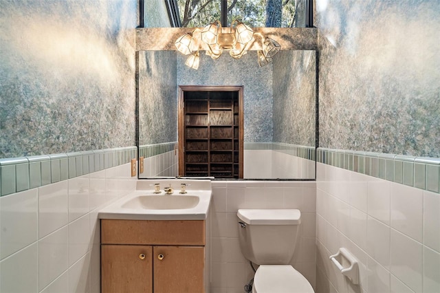 bathroom featuring vanity, tile walls, and toilet