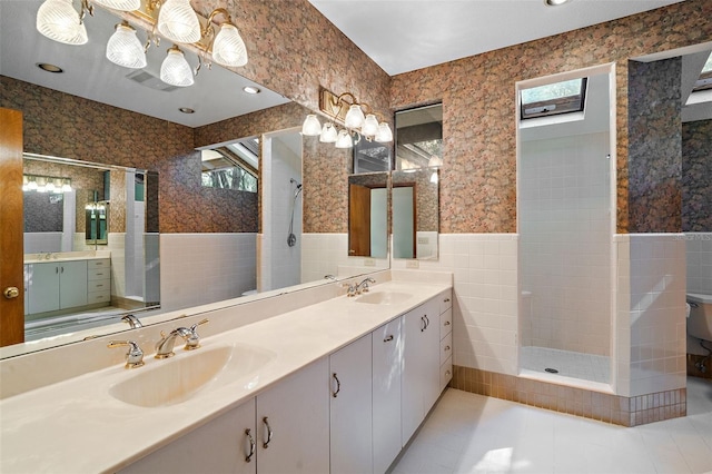 bathroom with vanity, a tile shower, and tile walls