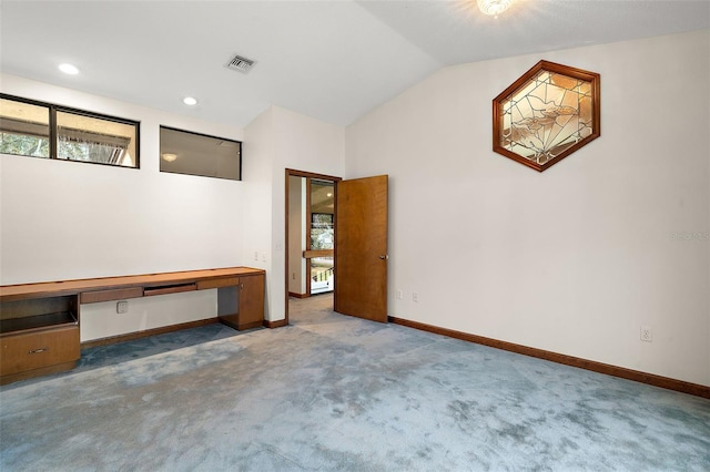 carpeted empty room featuring built in desk, plenty of natural light, and lofted ceiling