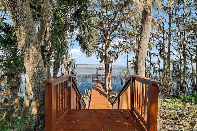 wooden deck with a water view and a boat dock