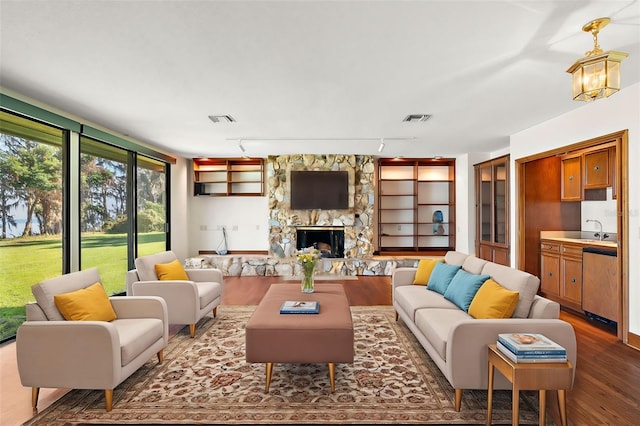 living room featuring sink, rail lighting, dark hardwood / wood-style floors, a chandelier, and a fireplace