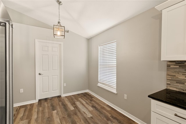 unfurnished dining area with dark hardwood / wood-style floors and vaulted ceiling