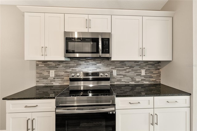 kitchen with white cabinets, appliances with stainless steel finishes, decorative backsplash, and dark stone counters