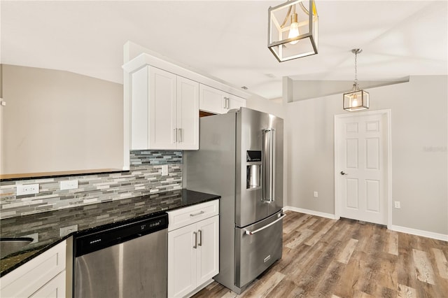 kitchen with tasteful backsplash, stainless steel appliances, vaulted ceiling, decorative light fixtures, and white cabinetry