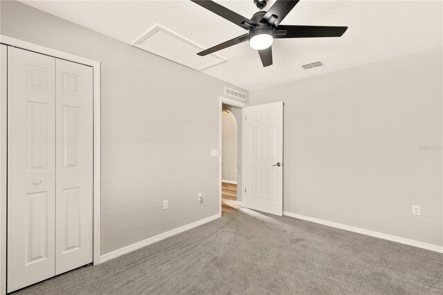 unfurnished bedroom featuring a closet, light colored carpet, and ceiling fan