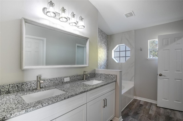 bathroom with hardwood / wood-style flooring, vanity, and tiled shower / bath combo