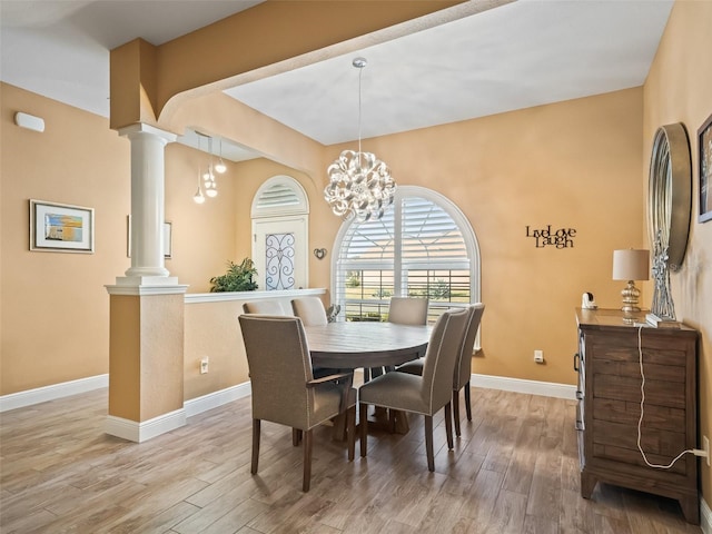 dining space featuring ornate columns, a notable chandelier, and hardwood / wood-style flooring