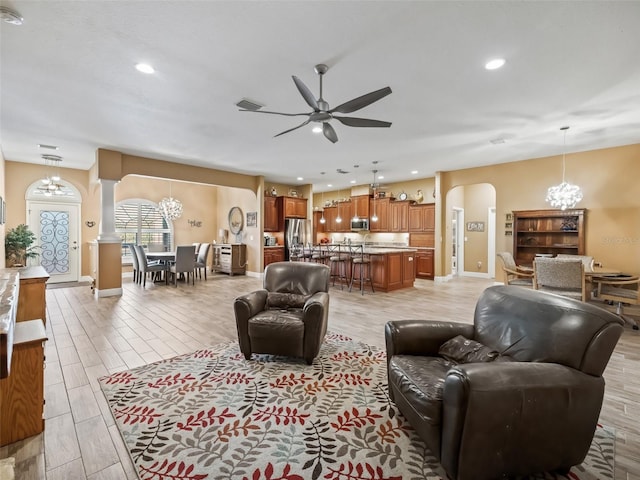 living room with ceiling fan with notable chandelier