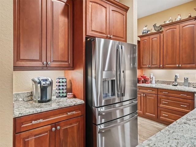 kitchen featuring light hardwood / wood-style floors, light stone countertops, and stainless steel refrigerator with ice dispenser