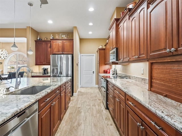 kitchen featuring sink, stainless steel appliances, light stone counters, decorative light fixtures, and light wood-type flooring