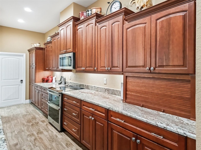 kitchen with light wood-type flooring, light stone countertops, and stainless steel appliances