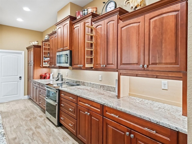 kitchen featuring light wood-type flooring, stainless steel appliances, and light stone counters