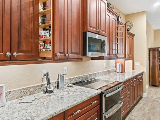 kitchen featuring appliances with stainless steel finishes, light hardwood / wood-style flooring, and light stone counters