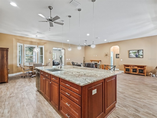 kitchen featuring light stone counters, sink, pendant lighting, and light hardwood / wood-style flooring