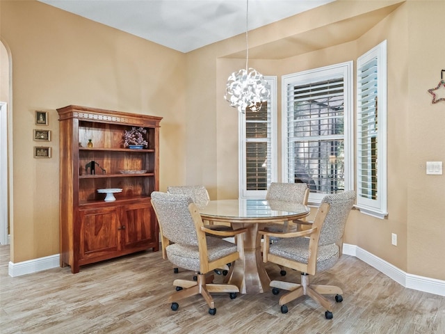 dining space with light hardwood / wood-style floors and an inviting chandelier