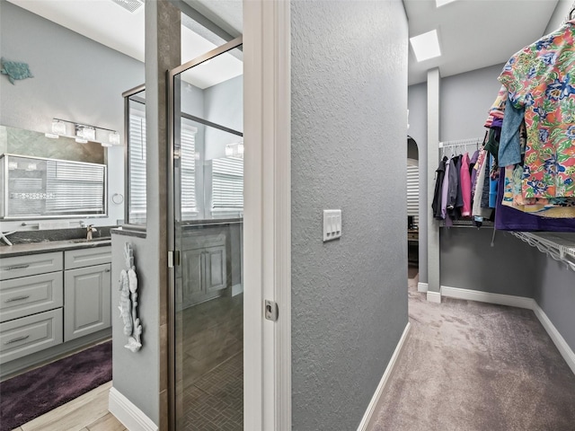 bathroom with a skylight, a shower with door, and vanity